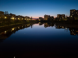 Obraz premium City skyline reflected in calm river at twilight with pink and blue dusk sky