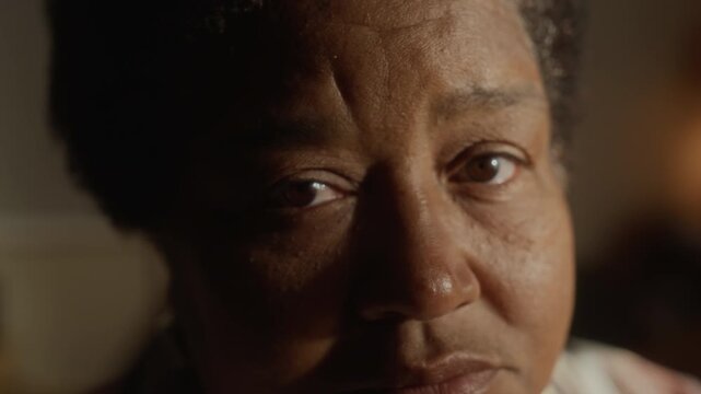 Portrait of senior African American woman turning head to look directly into camera. Footage is ideal for commercial campaigns focusing on senior mental health, loneliness, or geriatric care