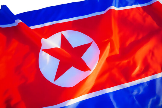 Flag of North Korea background, close-up. North Korea flag waving in wind, showing the red background and white star emblem against blue border. Flag of the Democratic People's Republic of Korea