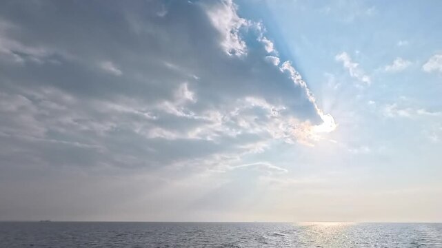 Time-lapse of powerful sunbeams breaking through clouds over the blue ocean