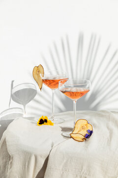Two rose wine glasses with summer cocktails and dried fruit appetizers