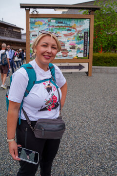 Blonde American tourist poses near a map at the Fushimi Inari Shrine