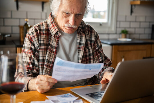Senior man reviewing bills in home kitchen