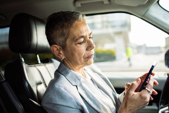 Senior businesswoman using smartphone in parked car