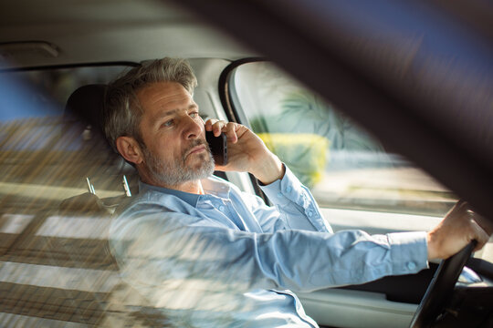 Middle-aged man talking on phone while driving car