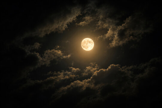 Full moon glowing through dramatic dark clouds at night