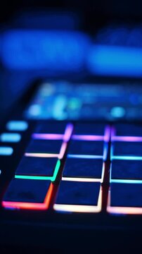Close-up view of a red midi controller with rubber pads glowing in rhythmic patterns under dim studio lighting. Concept of electronic music production, creative beat making, and nightlife.