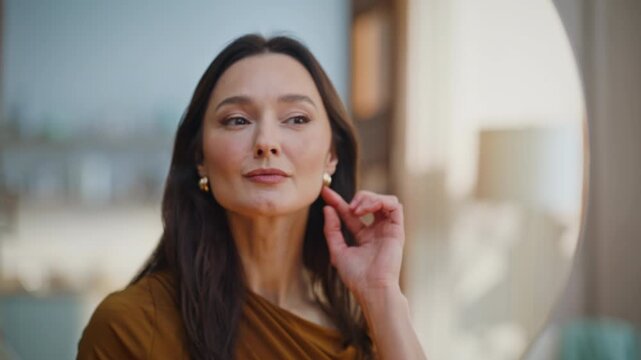 Brunette checking earrings preparing to luxury party home closeup. Smiling woman