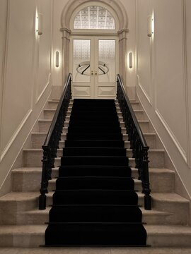 Symmetrical staircase leading to double doors in a sophisticated interior, showcasing luxury architecture and refined design.