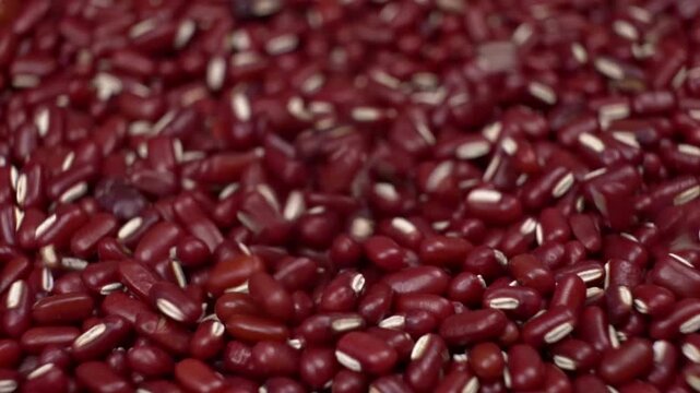 Extreme close-up view of red beans falling and scattering on a textured surface