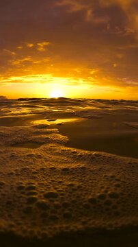 Slow motion video of a spectacular sunrise viewed from the Bogey Hole at Bronte Beach, Sydney, Australia, with calm rippling water reflecting golden morning light.