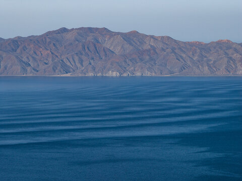 Aerial view of the rugged coastline and arid mountains meeting the deep blue waters of the Sea of Cortez in La Ventana, Baja California Sur, Mexico.