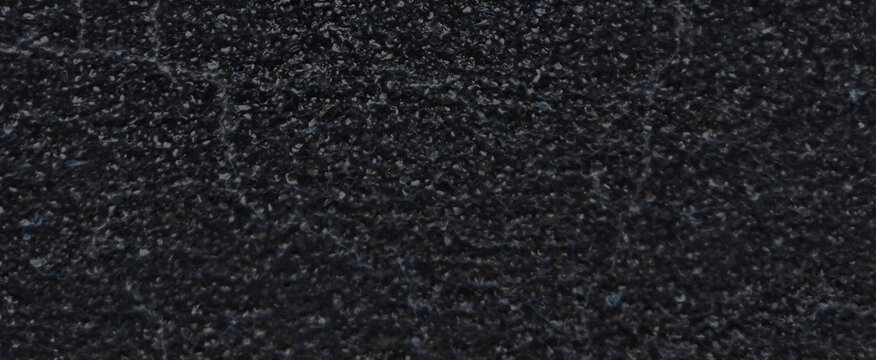 Black asphalt texture background, dark grainy road surface close-up, rough charcoal stone pavement material for construction and urban design