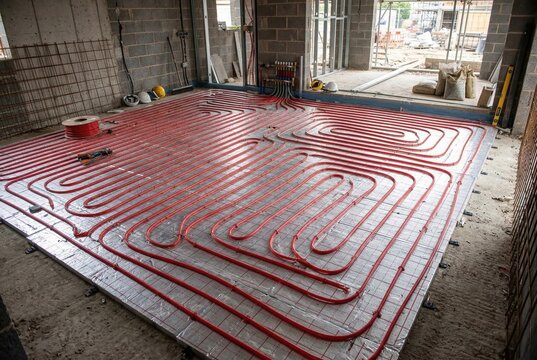 Red pex tubing laid out on insulation for a modern radiant floor heating system