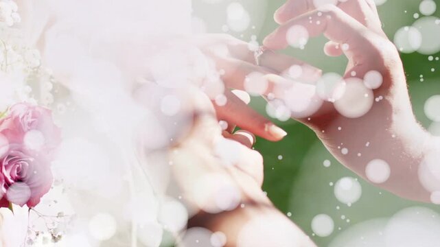 Man lifting ring and sliding onto woman's finger at wedding, bokeh clearing to reveal veil, roses