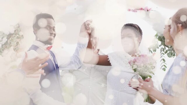 Officiant guiding ring exchange while bokeh overlay clearing, bride and groom celebrating marriage