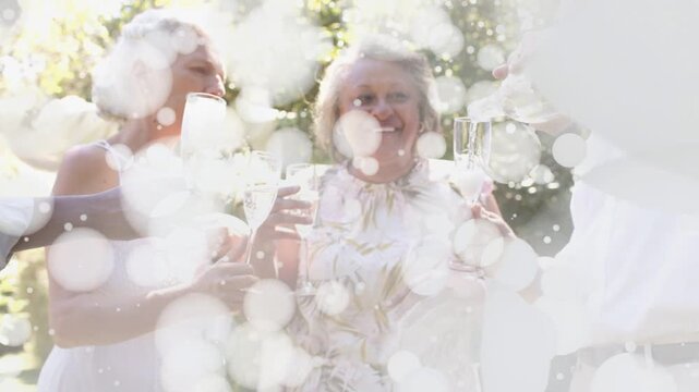 Sparkle bokeh overlay clearing, revealing group of four adults, pouring into flutes, toasting event
