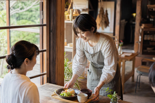 古民家カフェで笑顔で食事を提供する女性スタッフ