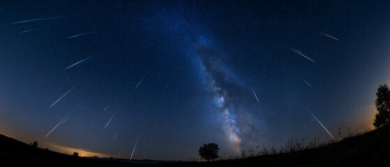 Meteor Shower Over Milky Way: A breathtaking panoramic view captures a vibrant meteor shower streaking across the starry night sky. © 琛明 周