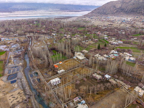 Aerial view of Katpanah Lake surrounded by poplar trees, agricultural fields, and residential buildings in the valley of Skardu, Gilgit Baltistan, Pakistan.