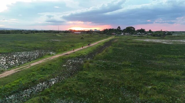 Drone view of a small rural pathway during sunset with golden twilight sky over Don Kaeo village.