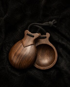 Traditional flamenco castanets resting on dark textured fabric.