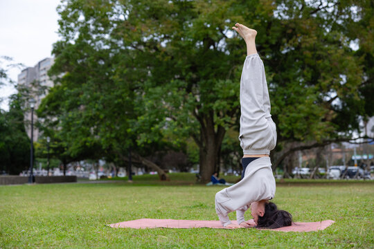 Woman practicing yoga headstand on grass