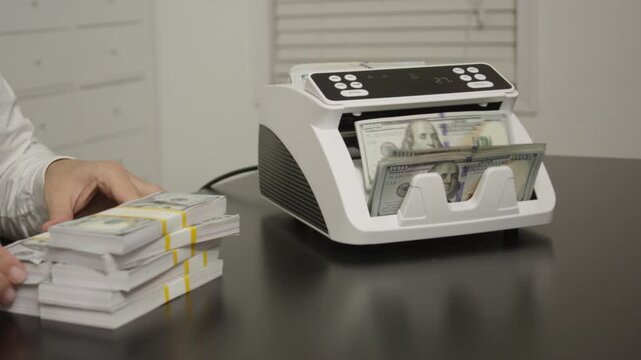 Business man hands with stacks of money in office. Business man counting money and managing cash. Office scene with money counting machine. Business concept with cash and digital work.