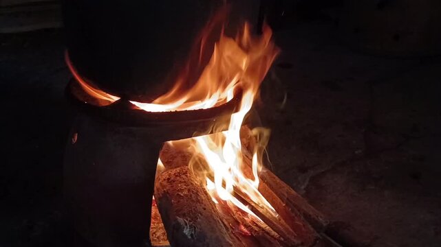 Close up of blazing fire burning firewood under a traditional clay stove at night