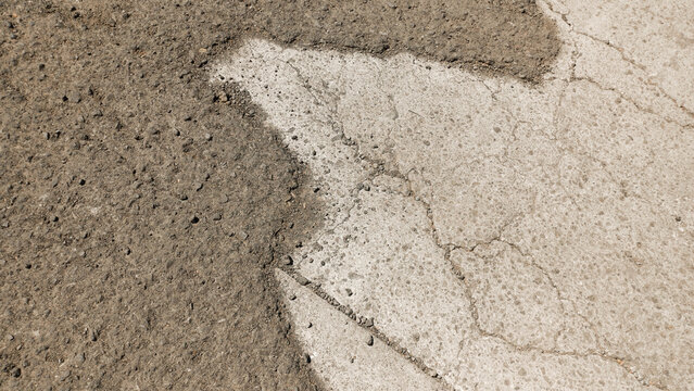 Damaged asphalt road surface texture with cracked concrete patch