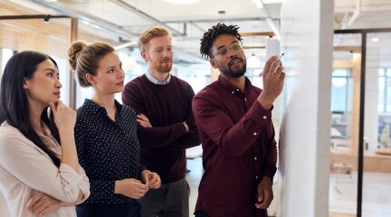 Obraz premium Diverse team brainstorms ideas at whiteboard