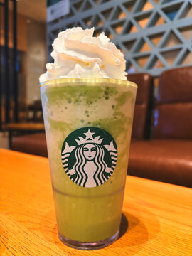 BANGKOK, THAILAND - JUNE 2026: A Starbucks Green Tea Cream Frappuccino Blended Beverage with Whipped Cream on a Wooden Table Inside a Caf&eacute;