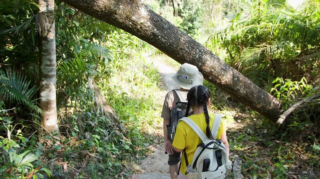 Two Asian Children Hiking Through a Lush Tropical Jungle Trail