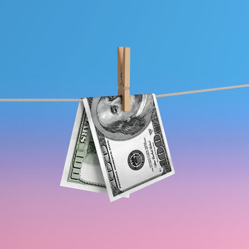 Money Laundering Concept. United States Dollar Banknotes Hanging From A Clothesline With Wooden Clothespin Against Blue And Pink Gradient Background. 3d Rendering