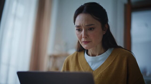 Worried freelancer watching laptop frustrated email in evening apartment closeup