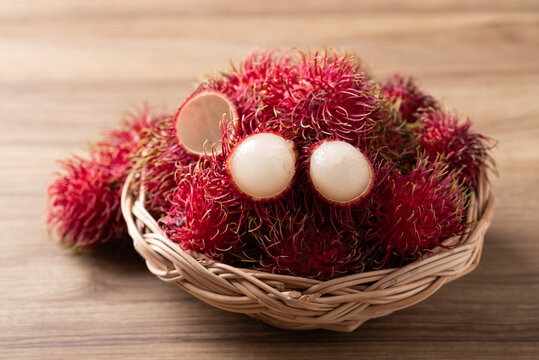 Fresh rambutan fruit in a wicker basket on wooden background, Tropical summer fruit in Thailand
