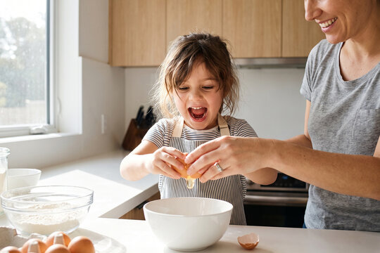 Mother Helping Child with Breakfast Cooking in Kitchen