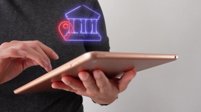 A person is holding a tablet with a bright bank icon and a locator pin.