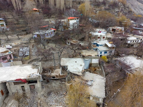 Aerial view of traditional stone houses and terraced orchards in Khaplu valley, featuring flat rooftops and bare trees in early spring in Khaplu, Gilgit Baltistan, Pakistan.