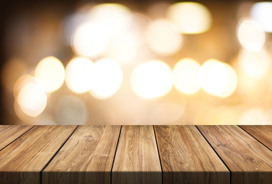 empty wooden table top on blur light golden bokeh of cafe restaurant, bar in a dark background, for your photo montage or product display, Space for placing items on the table.
