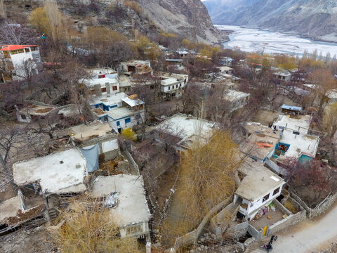 Aerial view of Khaplu valley featuring traditional stone houses with flat roofs, bare trees, and the winding river in the background in Khaplu, Gilgit Baltistan, Pakistan.