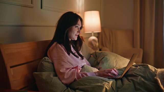 Brunette chatting laptop bed visiting dating site closeup. Smiling woman typing