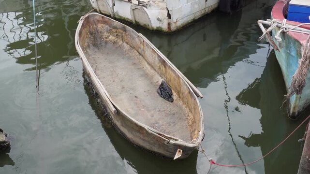 Old weathered boat floating peacefully in calm water dockside.