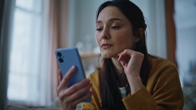 Brunette worried cellphone message receiving bad news in evening home closeup