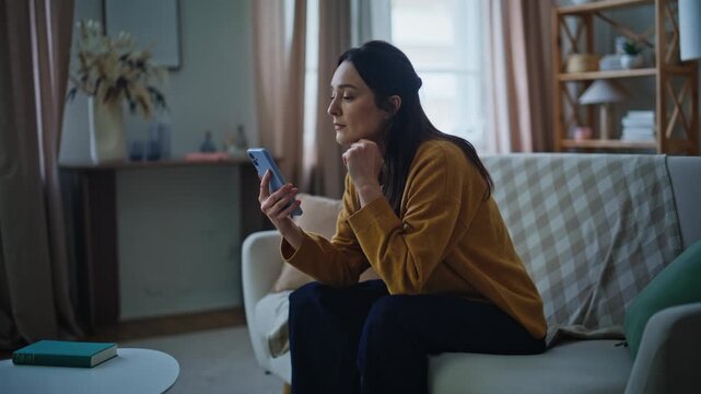 Lady disappointed smartphone notification sitting couch. Worried woman reading