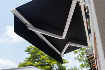 Obraz premium Modern retractable black awning provides shade on sunny day
