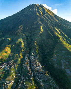 Aerial view of Nepal Van Java village nestled on the slopes of Mount Sumbing with terraced vegetable fields and morning light in Kecamatan Kaliangkrik, Jawa Tengah, Indonesia.