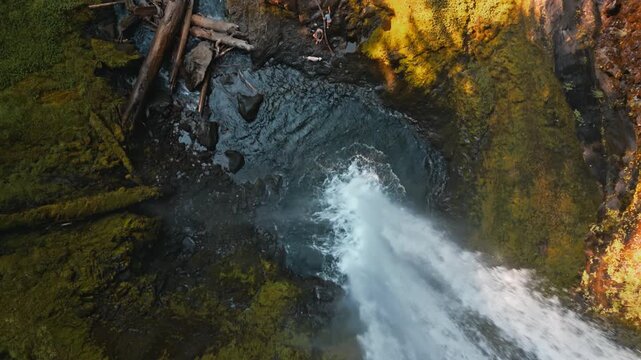 Aerial top down view over flowing stream of Falls Creek Falls lower tier waterfall surrounded by rugged cliffs, drone overhead