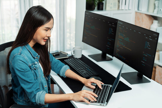Smiling young Asian in IT developer creating with typing online information on laptop with coding program data of application, wearing jeans shirt. surrounded by safety analysis two screen. Stratagem.