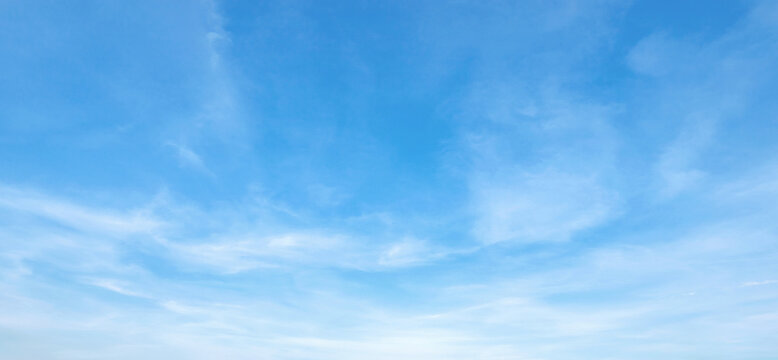 Soft clouds drift across a vast, serene blue sky
